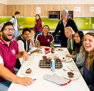 Group of laughing students sitting around table in Austin college kitchen